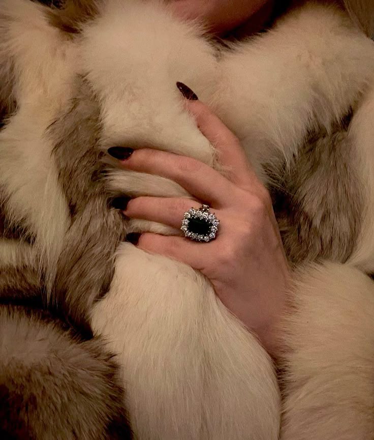 “Hand wearing a bold statement ring with fur background, showing how to look classy and expensive on a budget.”