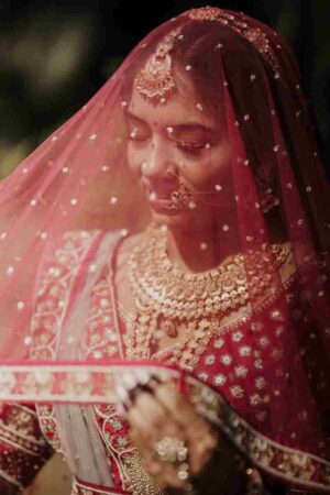 The ghunghat bridal dupatta draping style: net dupatta pinned at the crown, falling forward over the face during ceremonies.
